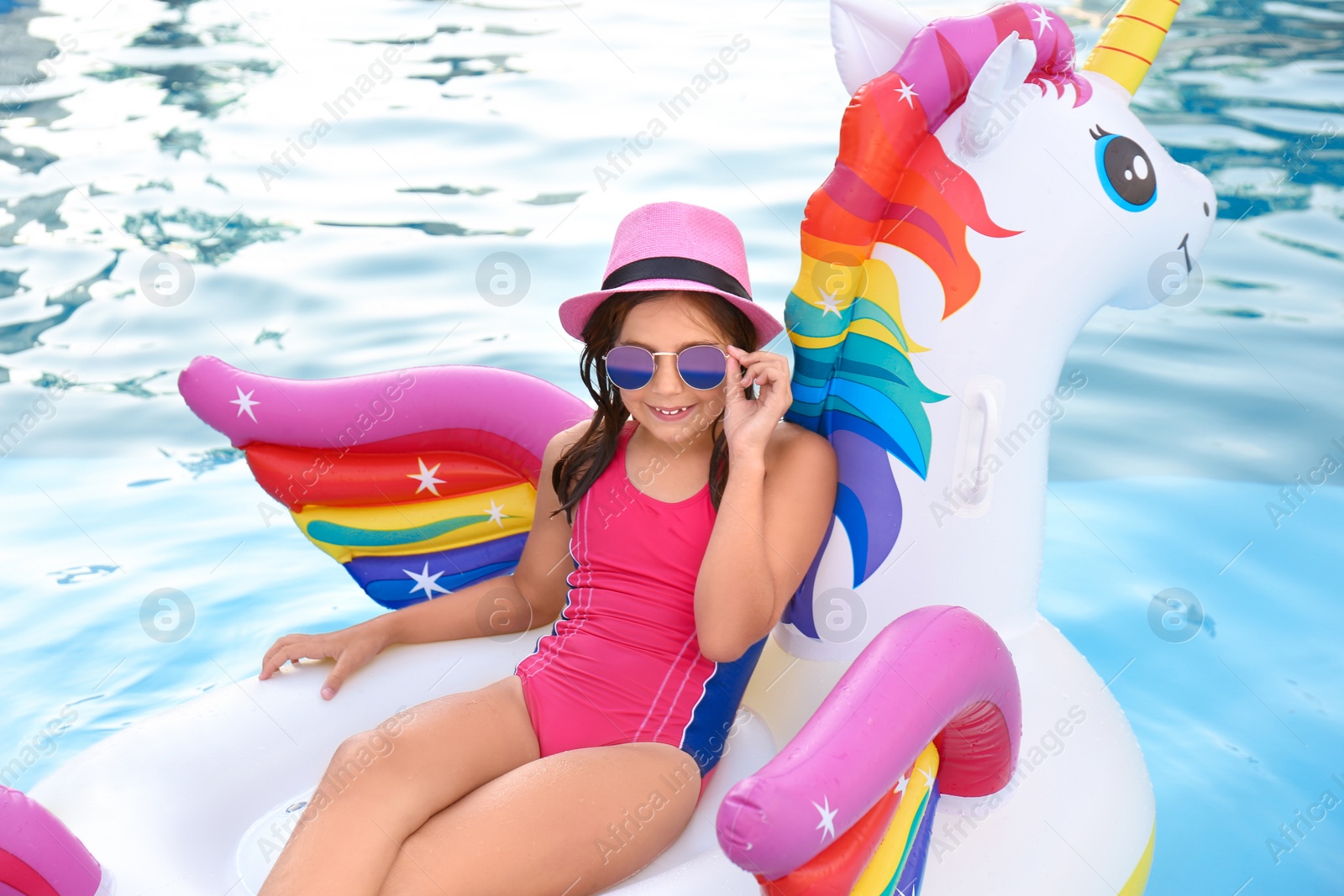 Photo of Happy cute girl on inflatable unicorn in swimming pool