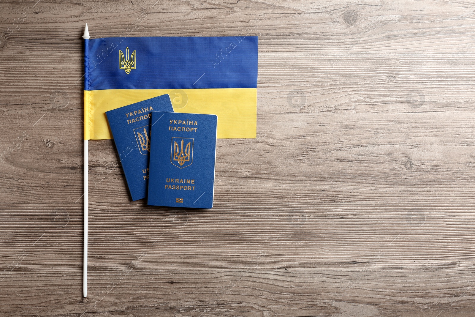 Photo of Ukrainian travel passports and national flag on wooden background, flat lay with space for text. International relationships