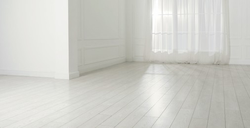 Photo of Empty room with white walls, large window and laminated flooring