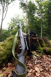 Hunting rifle, binoculars and cartridges on tree stump outdoors