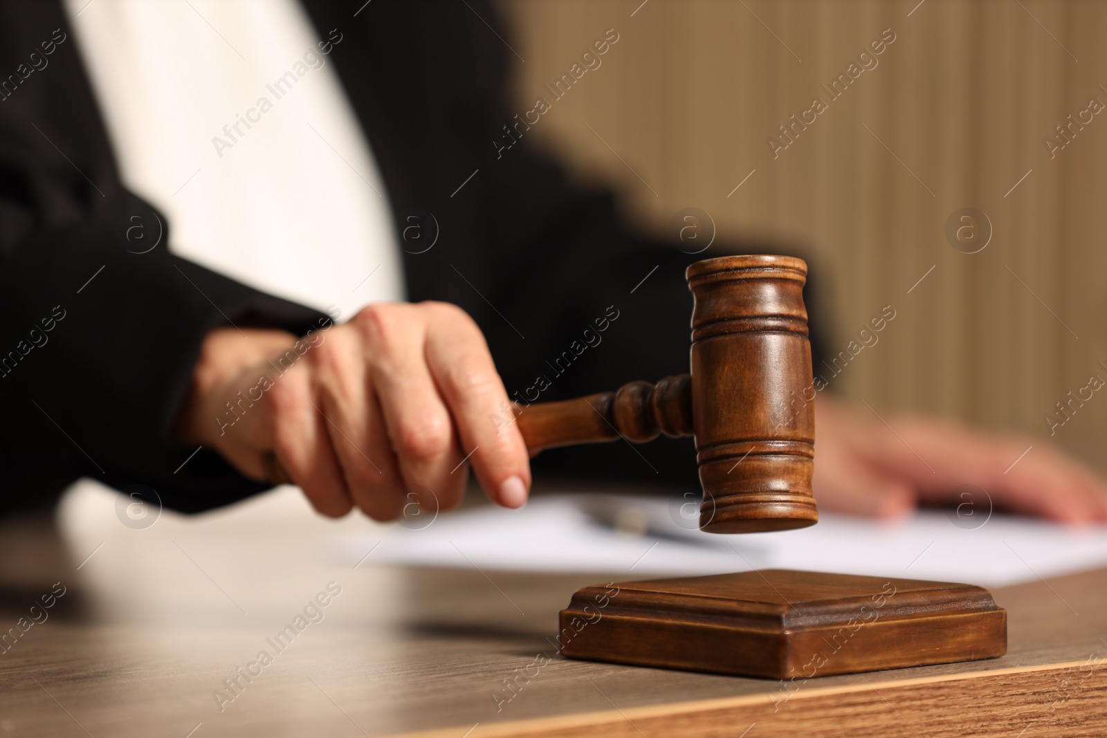 Photo of Judge striking mallet at wooden table indoors, closeup