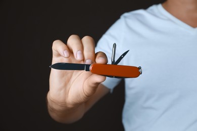 Man holding multitool on dark background, closeup