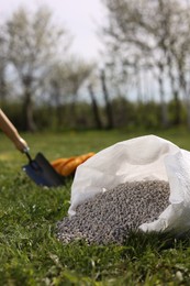 Photo of Granulated fertilizer in sack on green grass outdoors, closeup