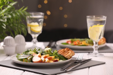 Delicious salad with peach slices served on white wooden table