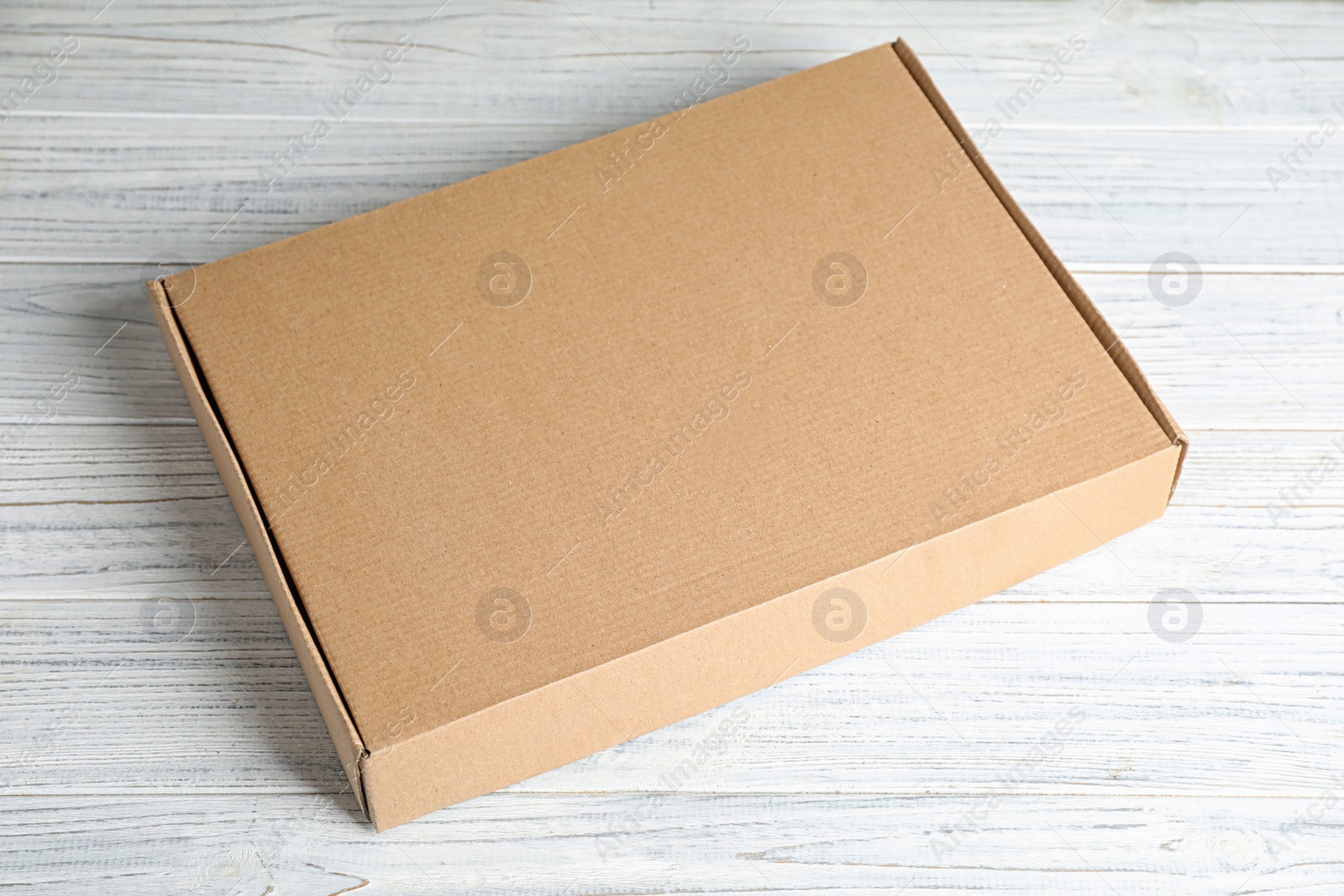 Photo of Closed cardboard box on white wooden table