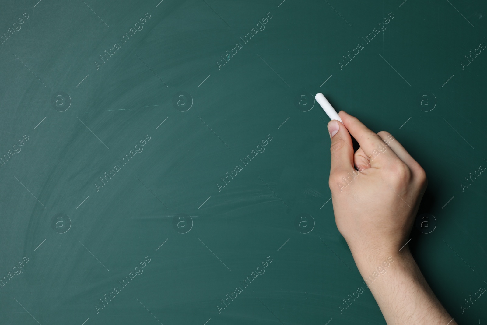 Photo of Teacher writing with chalk on green chalkboard, closeup. Space for text