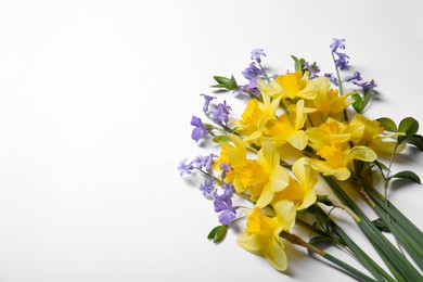 Beautiful yellow daffodils and periwinkle flowers on white background, top view. Space for text