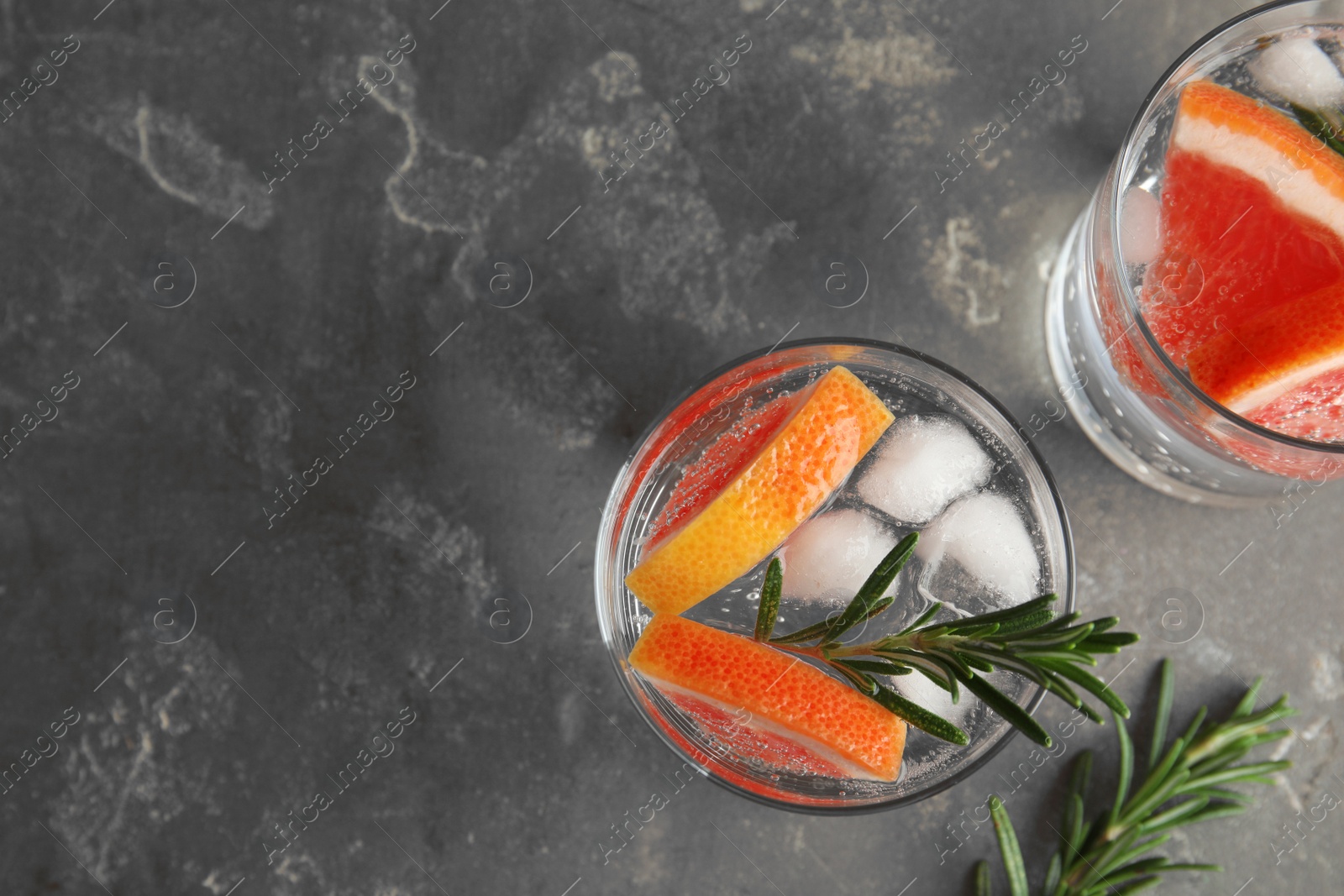 Photo of Glasses of infused water with grapefruit slices on grey table, top view. Space for text