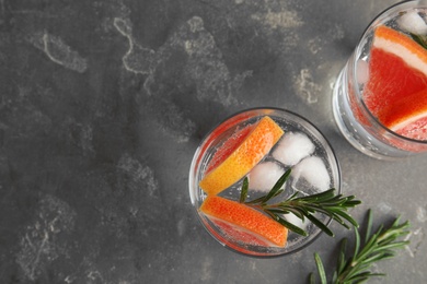 Glasses of infused water with grapefruit slices on grey table, top view. Space for text