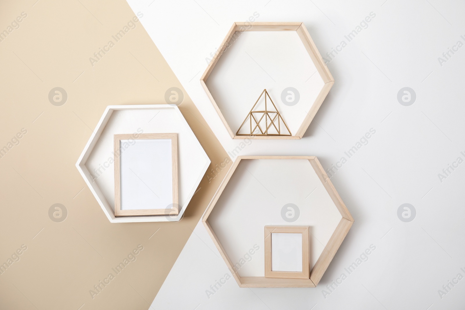 Photo of Honeycomb shaped shelves with decorative elements on color wall
