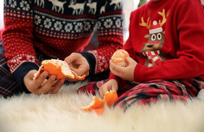 Photo of Father and little daughter peeling tangerines on faux fur, closeup