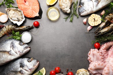 Frame of fresh raw dorado fish and different seafood on grey table, top view. Space for text