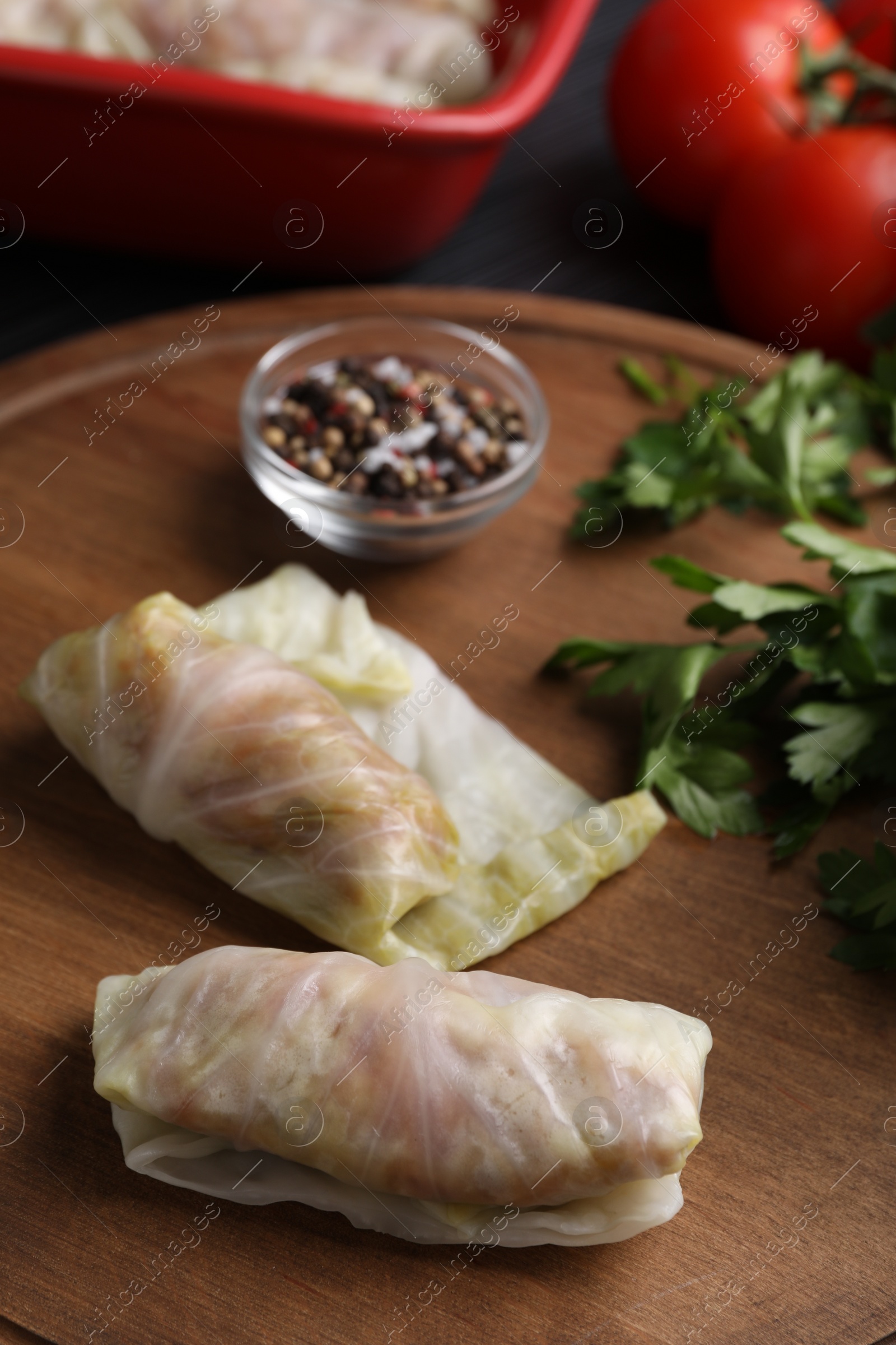 Photo of Uncooked stuffed cabbage rolls on wooden board, closeup