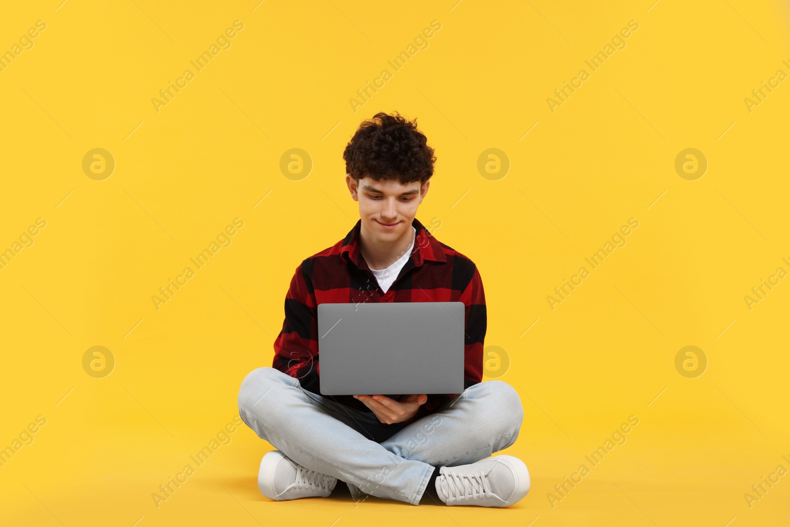 Photo of Portrait of student with laptop on orange background