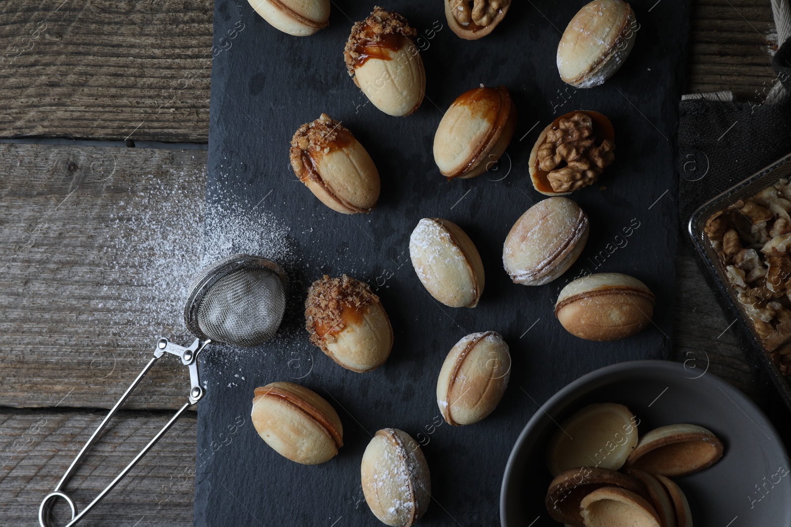 Photo of Freshly baked homemade walnut shaped cookies, nuts and flour on wooden table, flat lay. Space for text