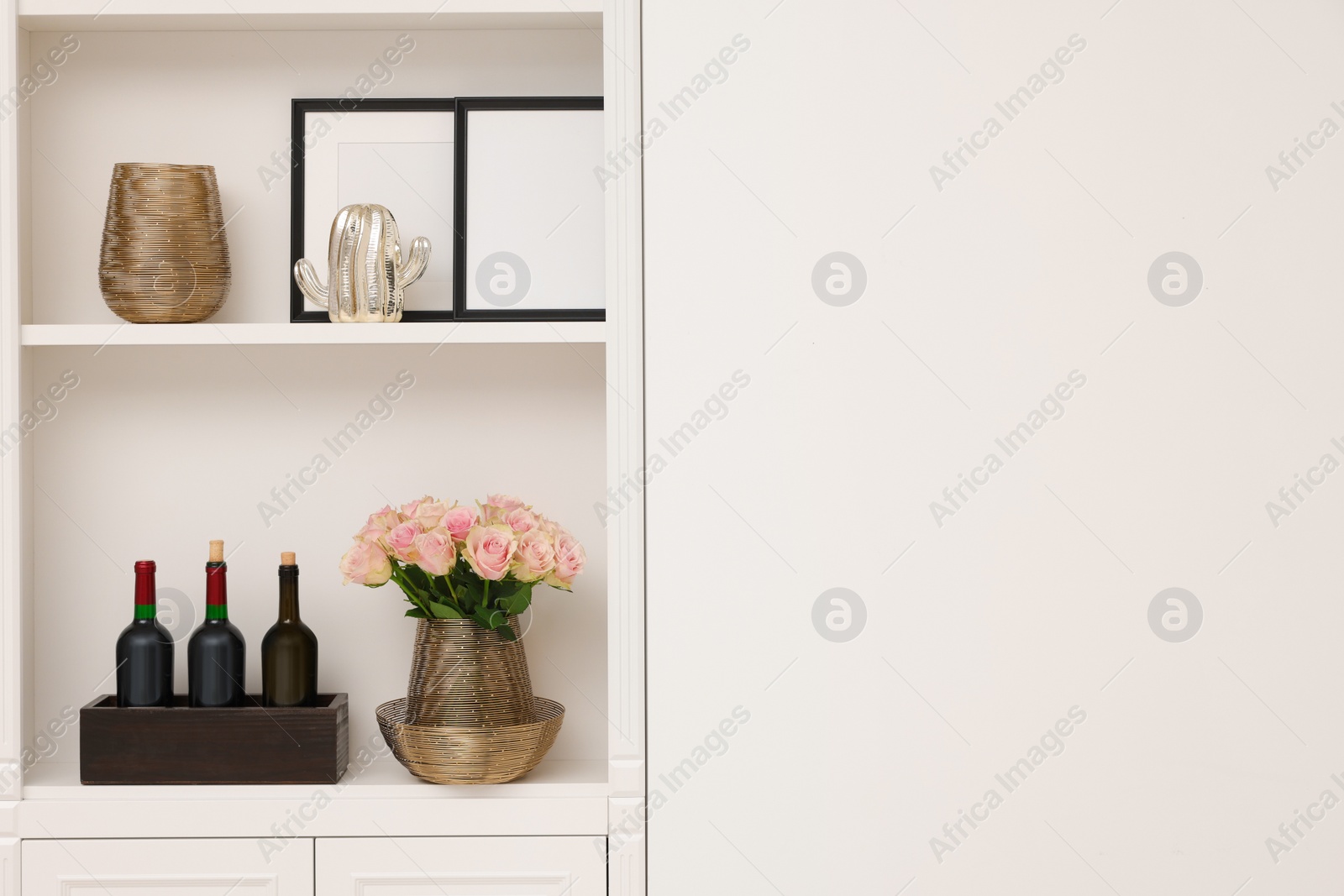 Photo of Shelves with different decor near white wall, space for text. Interior design