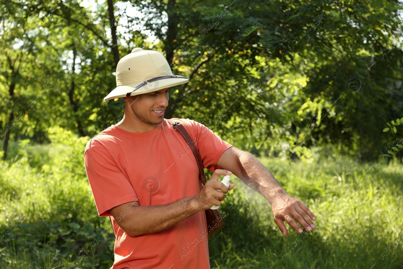 Photo of Man spraying tick repellent on arm during hike in nature