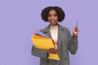 African American intern with folders and pen on purple background