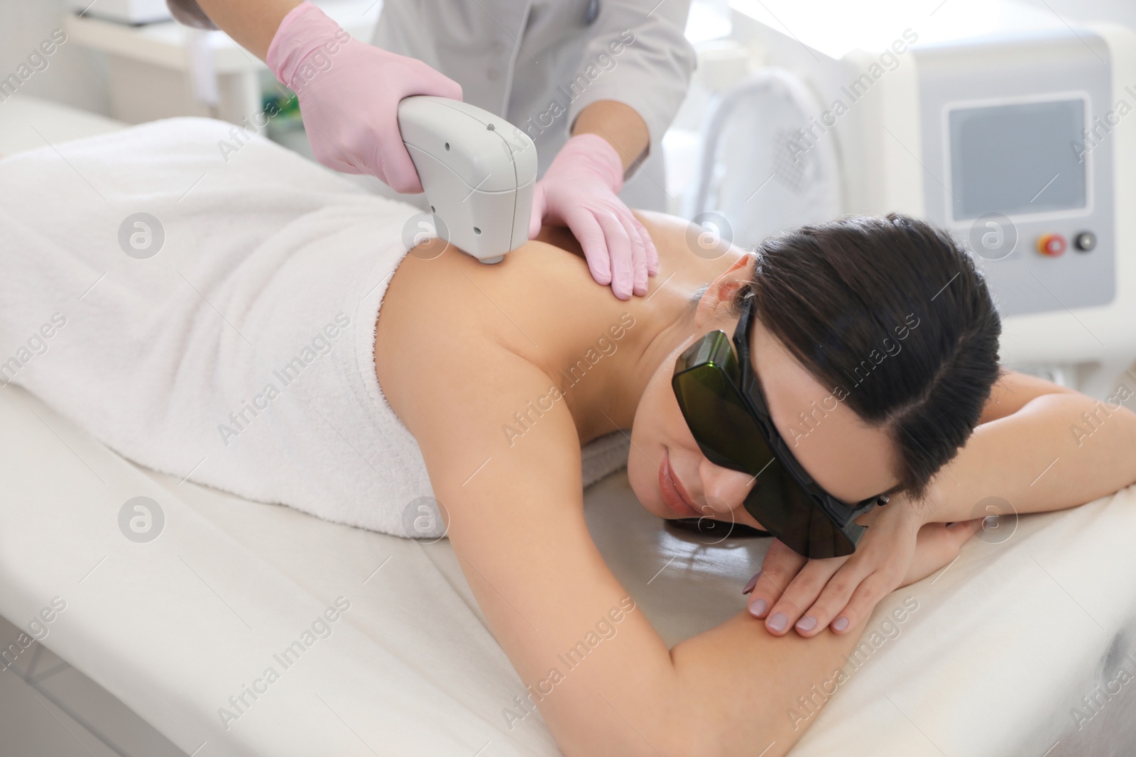 Photo of Young woman undergoing laser epilation procedure in beauty salon