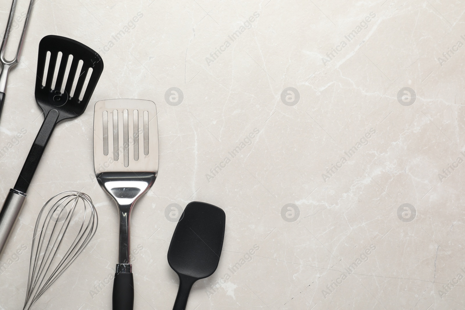 Photo of Different spatulas, whisk and carving fork on light marble table, flat lay. Space for text