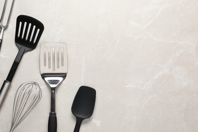 Photo of Different spatulas, whisk and carving fork on light marble table, flat lay. Space for text