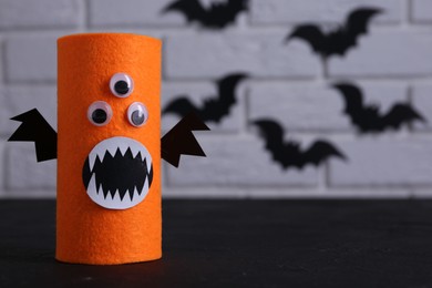 Photo of Spooky monster on black table, space for text. Handmade Halloween decoration