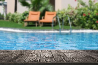 Image of Empty wooden surface near outdoor swimming pool with clear water. Space for design