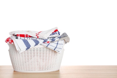 Photo of Basket with clean laundry on wooden table, white background