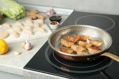 Photo of Cooking gyoza on frying pan with hot oil in kitchen