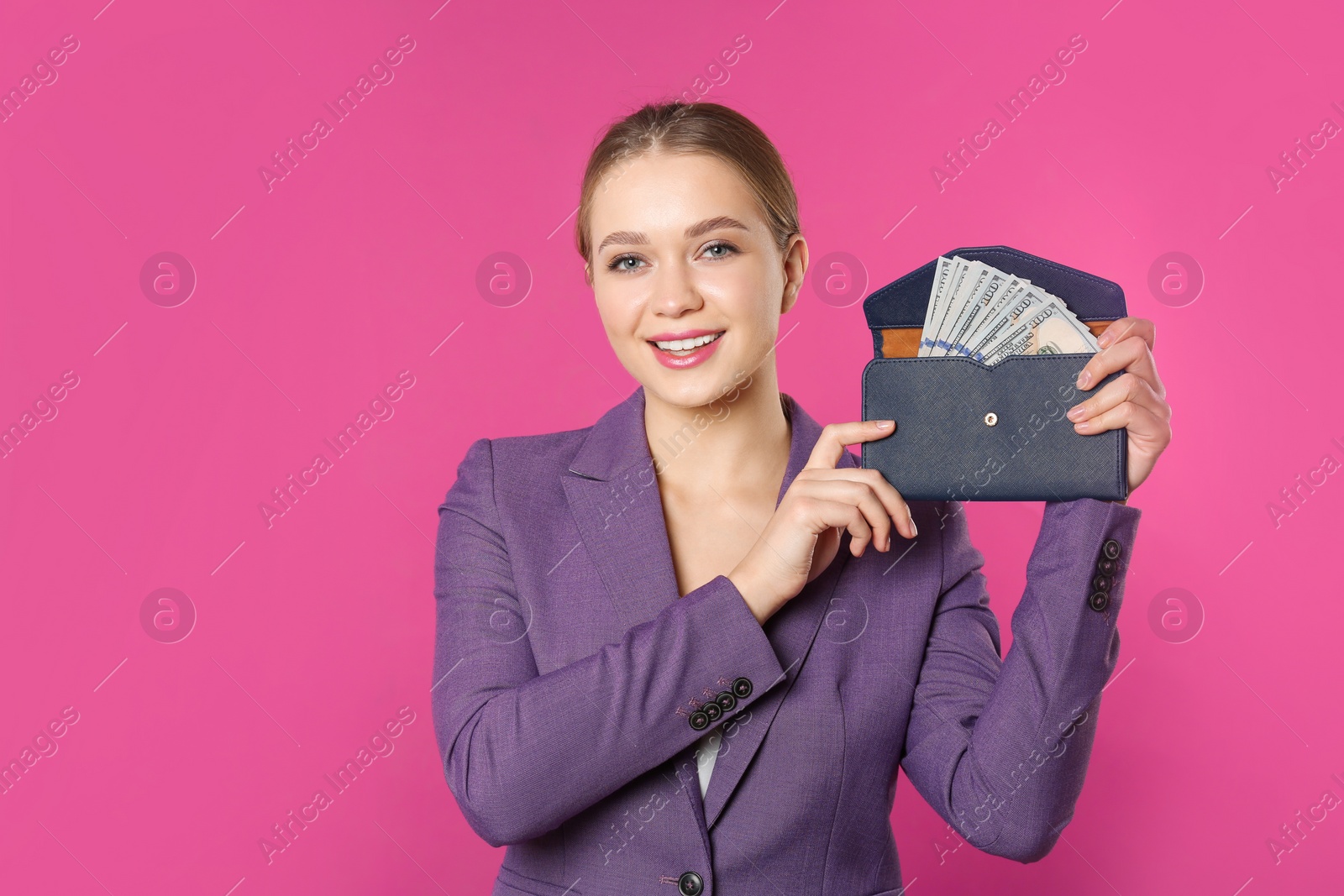 Photo of Happy young businesswoman with wallet full of money on color background