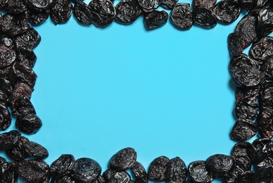 Photo of Frame made of tasty prunes on color background, top view with space for text. Dried fruit as healthy snack