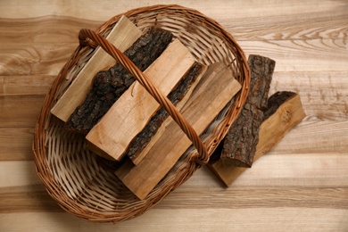 Wicker basket and firewood on floor indoors, flat lay