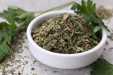 Photo of Dried parsley and fresh leaves on light grey table, closeup