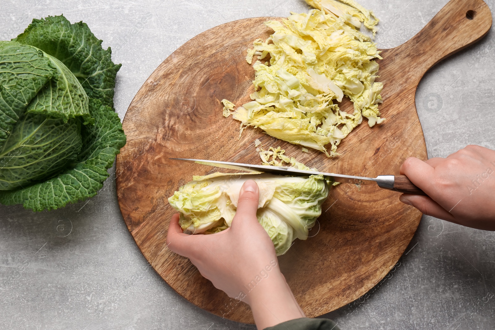 Photo of Woman cutting fresh ripe cabbage at grey table, top view