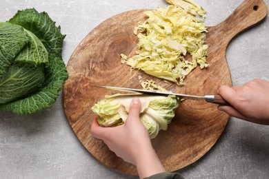 Woman cutting fresh ripe cabbage at grey table, top view