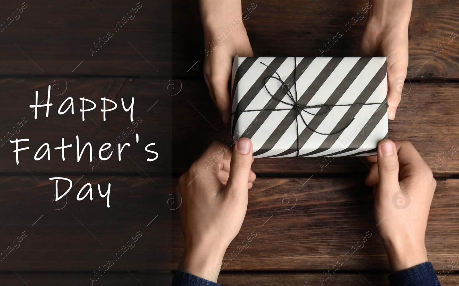 Image of Daughter giving present to her dad over wooden table, top view. Happy father's day