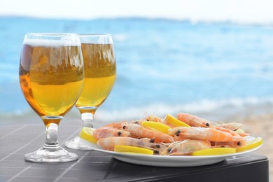 Cold beer in glasses and shrimps served with lemon on beach