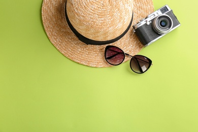Photo of Stylish hat, camera and sunglasses on color background, top view
