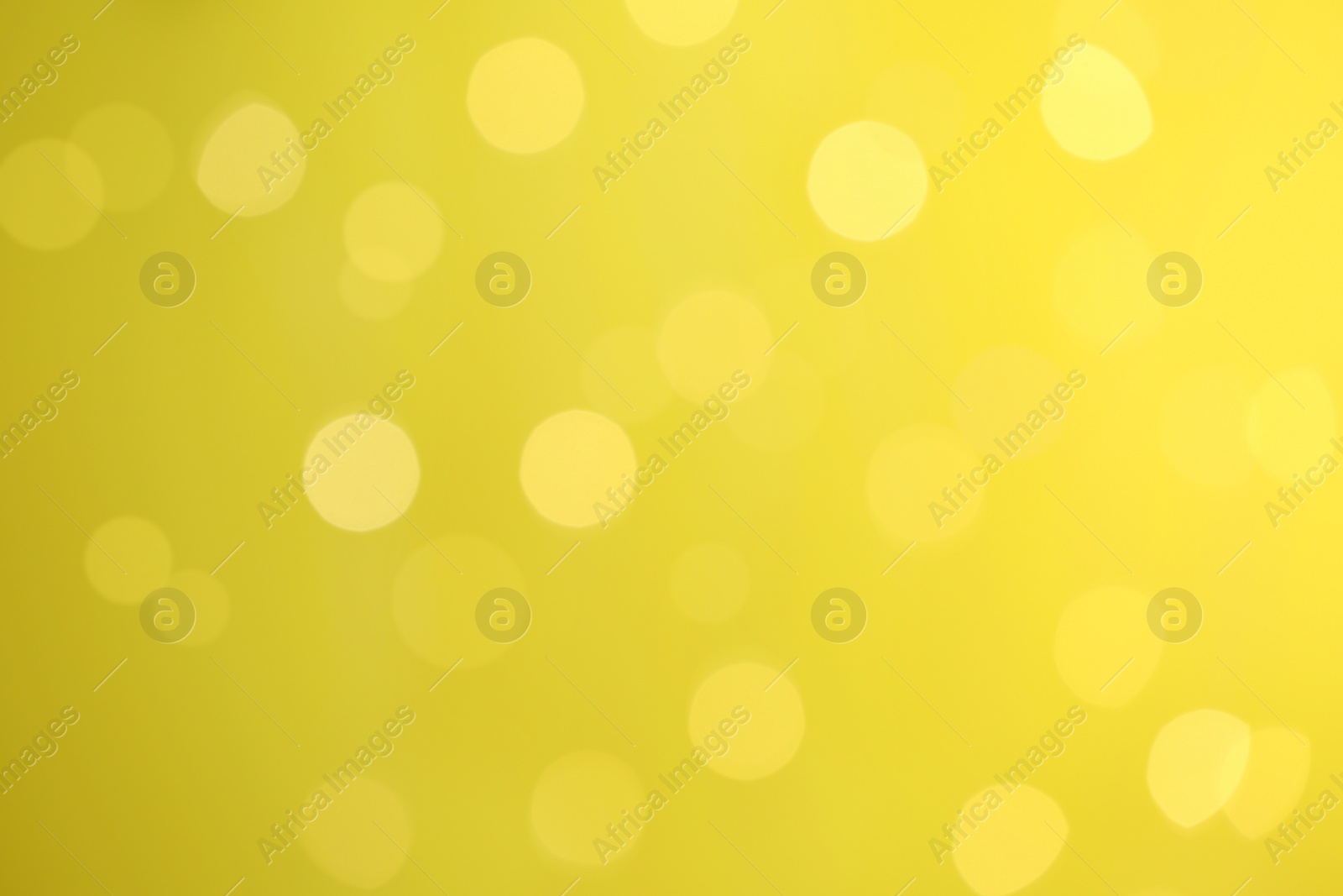 Photo of Blurred view of festive lights on yellow background. Bokeh effect