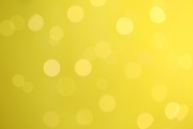 Photo of Blurred view of festive lights on yellow background. Bokeh effect