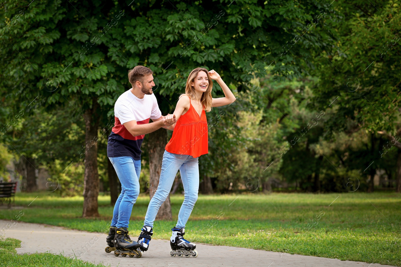 Photo of Young happy couple roller skating in summer park