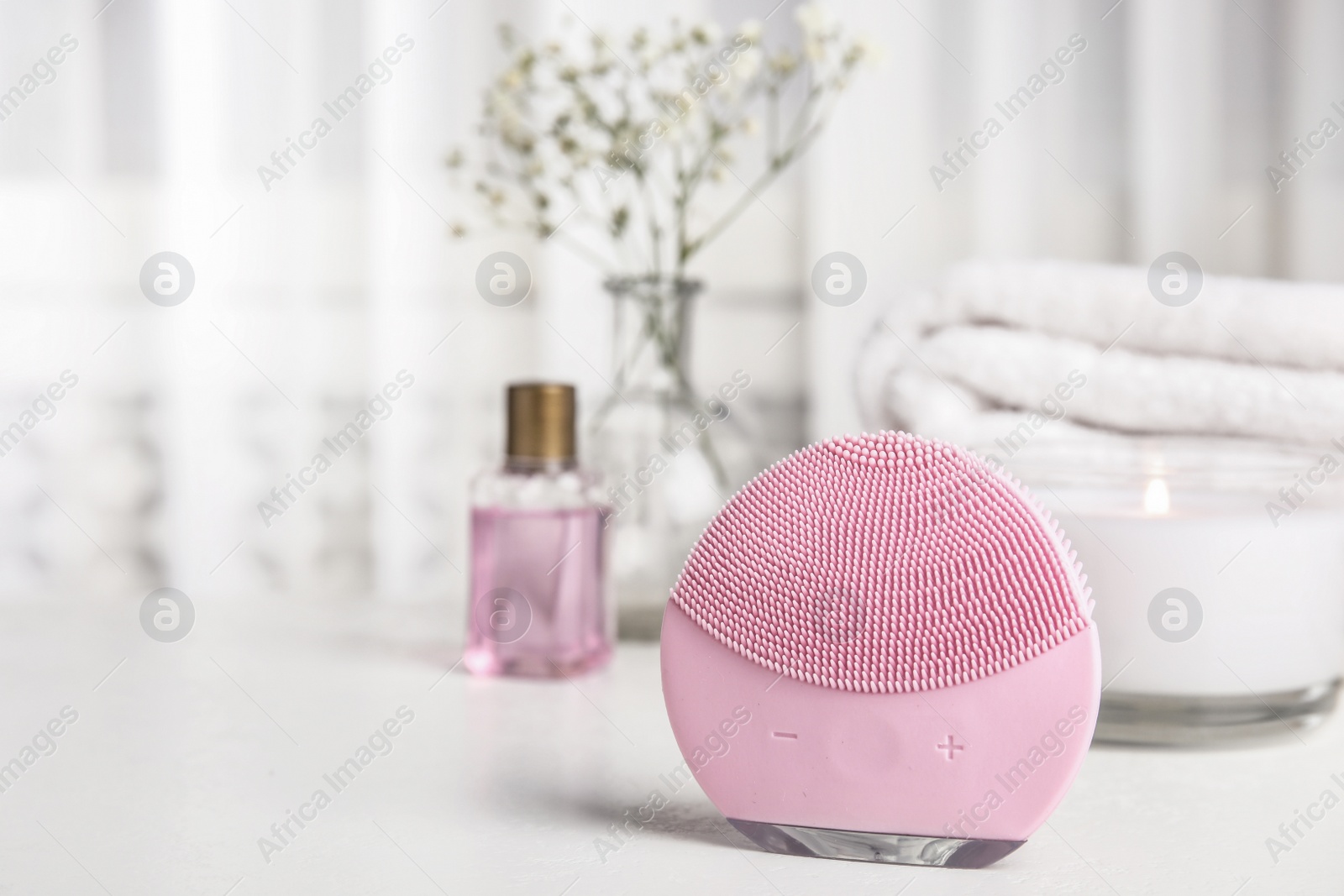 Photo of Modern face cleansing brush on white table. Cosmetic accessory