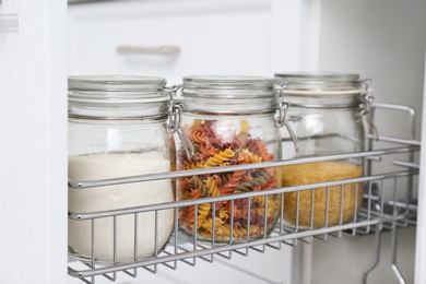 Photo of Open drawer with jars of food in kitchen, closeup