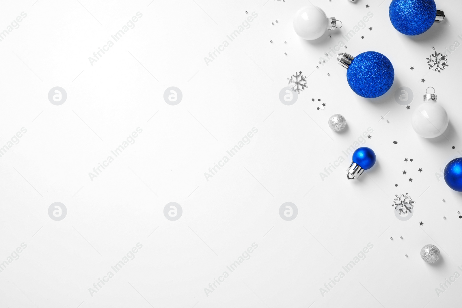 Photo of Colorful Christmas balls and sparkles on white background, top view. Space for text