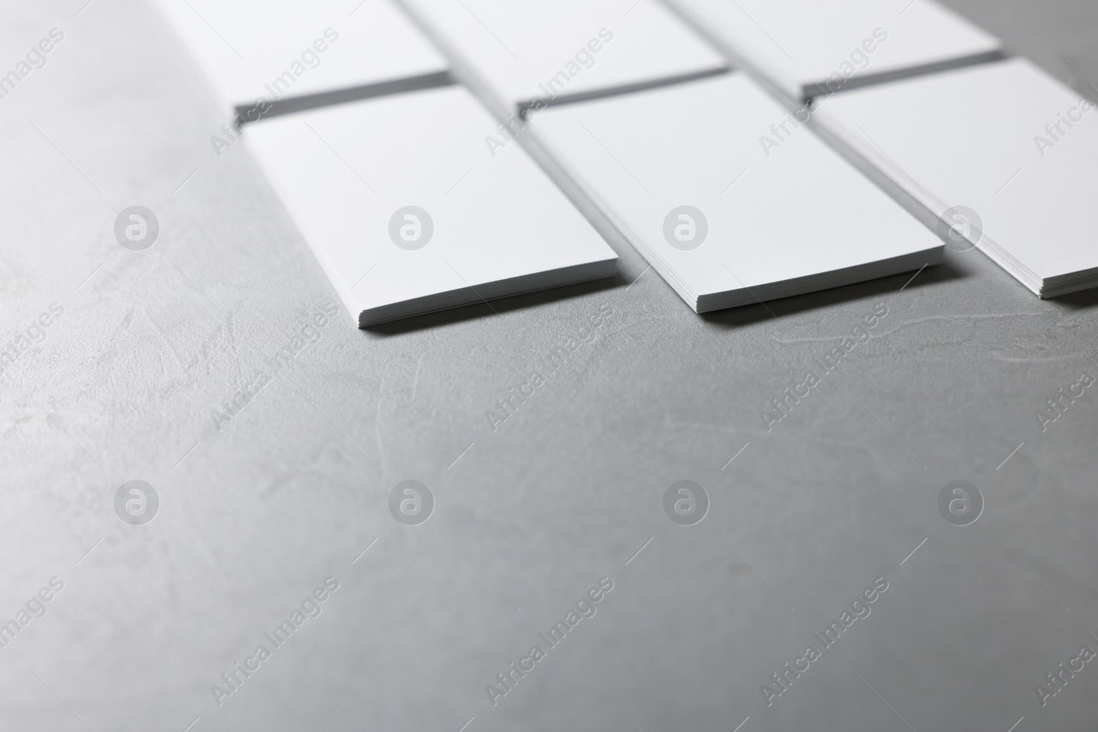 Photo of Blank business cards on light grey textured table, closeup. Mockup for design