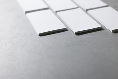 Blank business cards on light grey textured table, closeup. Mockup for design