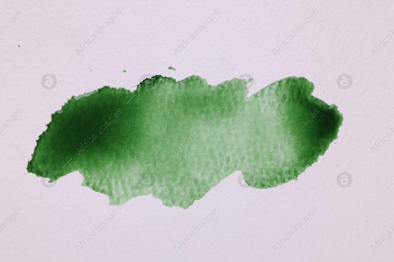 Photo of Blot of green watercolor paint on white paper, top view