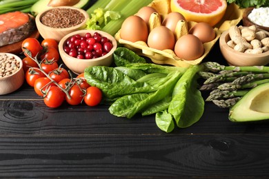 Photo of Many different healthy food on black wooden table. Space for text