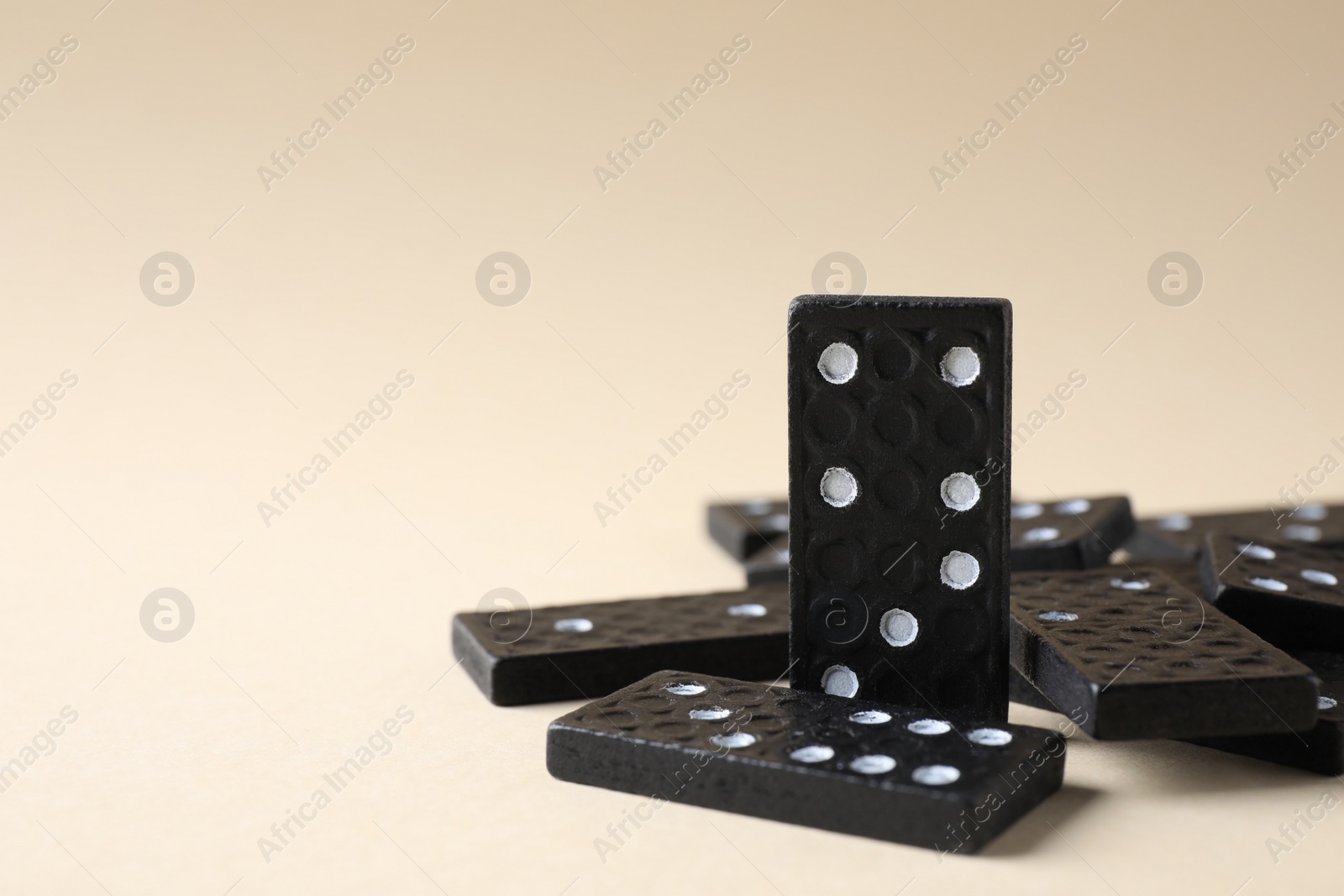 Photo of Black domino tiles on beige background. Space for text