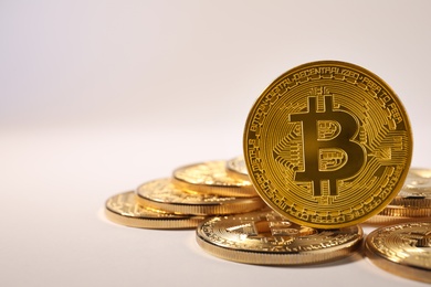 Photo of Shiny gold bitcoins on light background, space for text. Digital currency